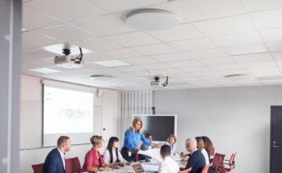 A group of professionals engaged in a high acoustic ceiling boardroom meeting.