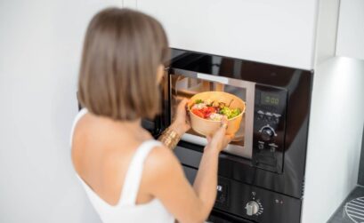 Woman heating food with microwave machine at home, female using modern kitchen appliances